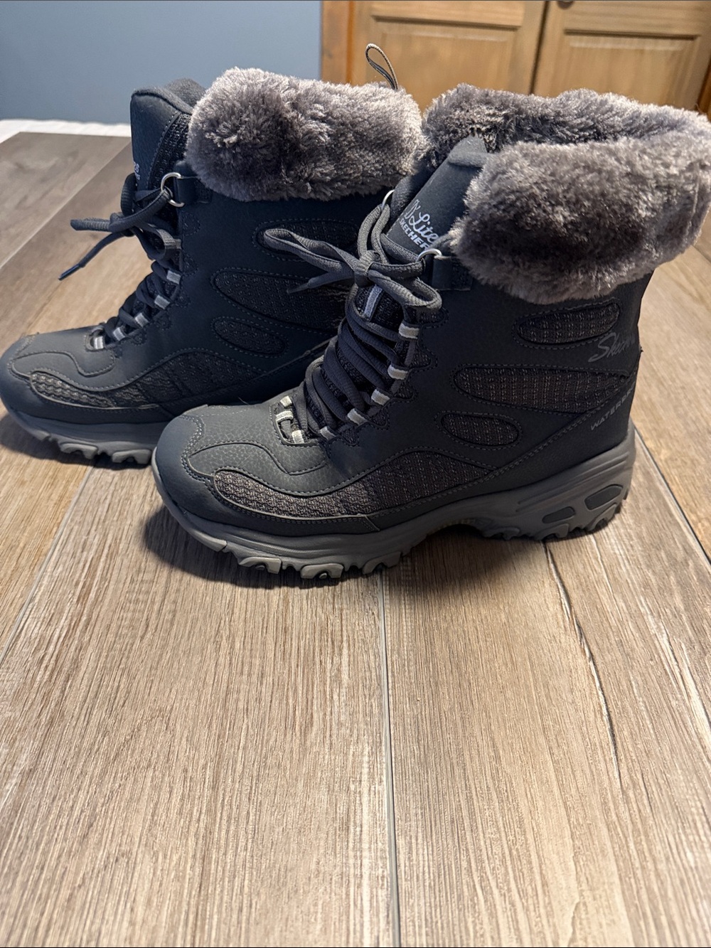 Skechers D'Lites Bomb Cyclone winter boots in a charcoal color, featuring a faux